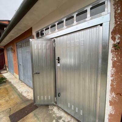Porta basculante zincata, predisposta all'automazione, completa di telaio superiore a vetro, portina pedonale e serrature